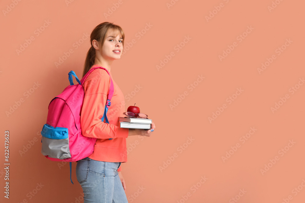 Female student with books, apple and backpack on color background