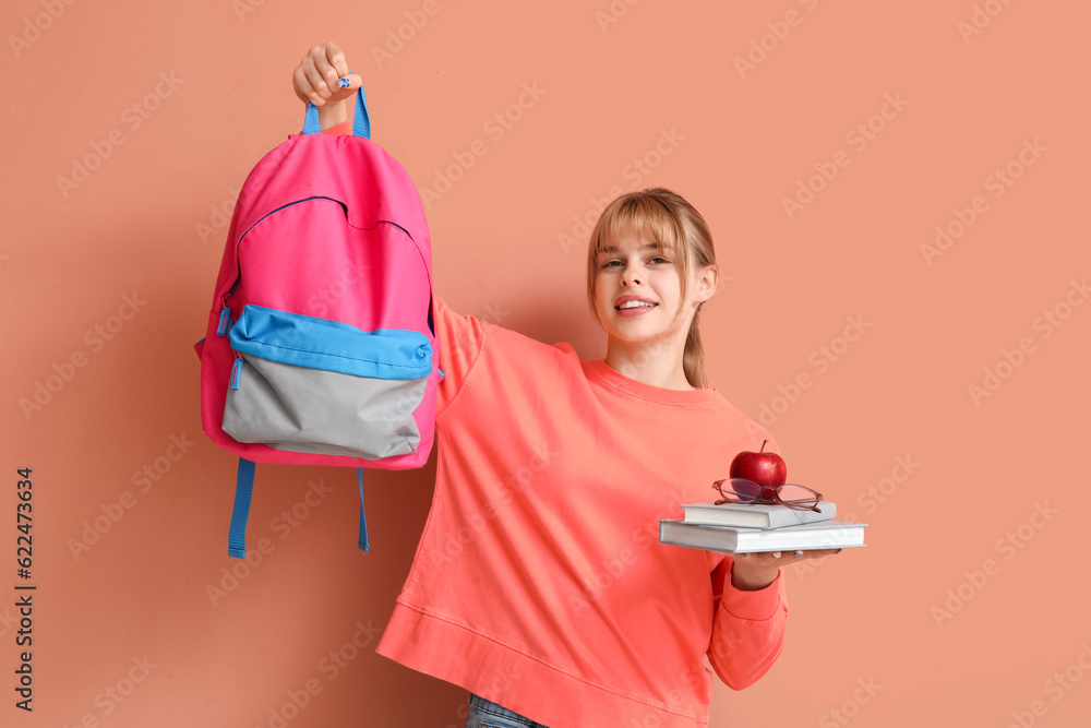 Female student with books, apple and backpack on color background