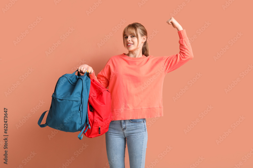 Female student with backpack showing muscles on color background