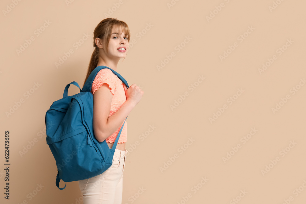 Female student with backpack on beige background