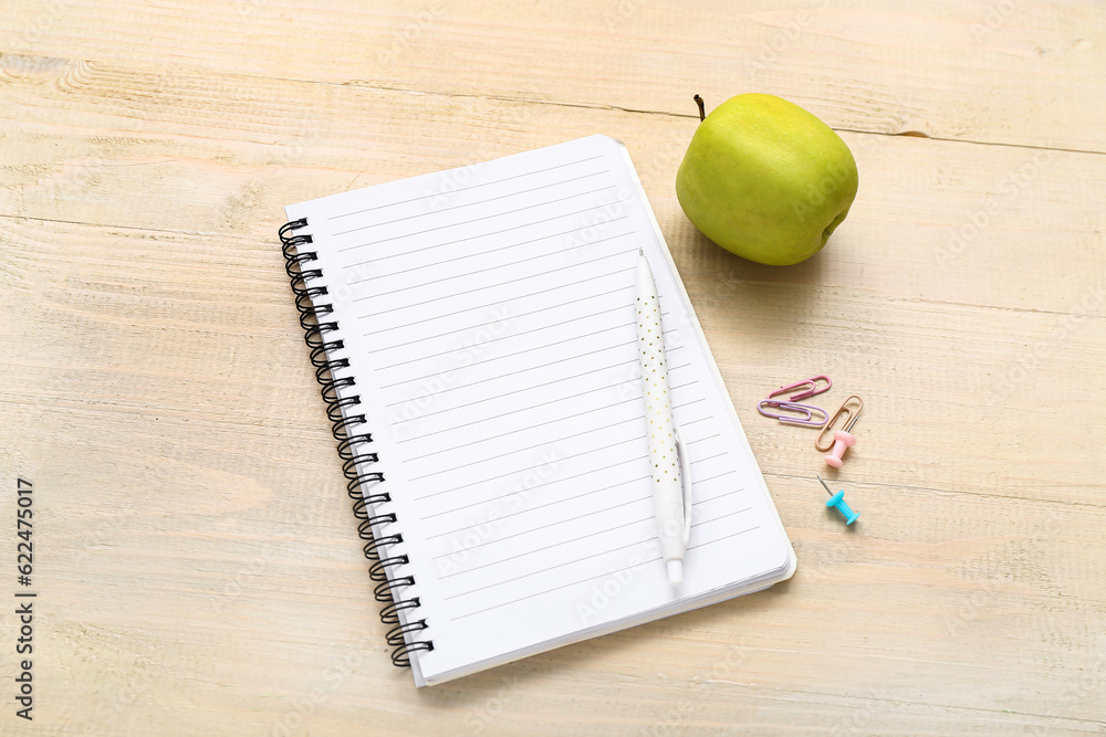 Blank notebook and different stationery on beige wooden background