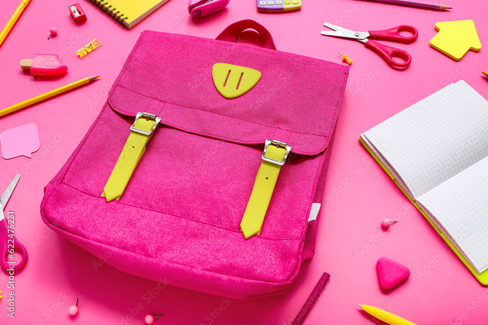 Backpack with blank notebook and different stationery on pink background