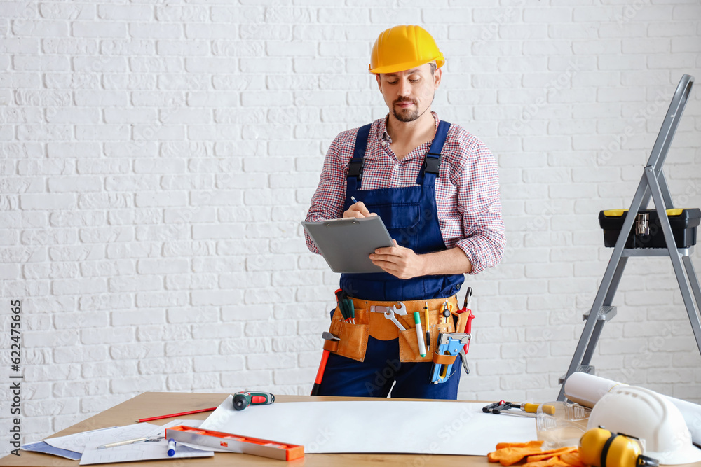 Male builder with clipboard working in room