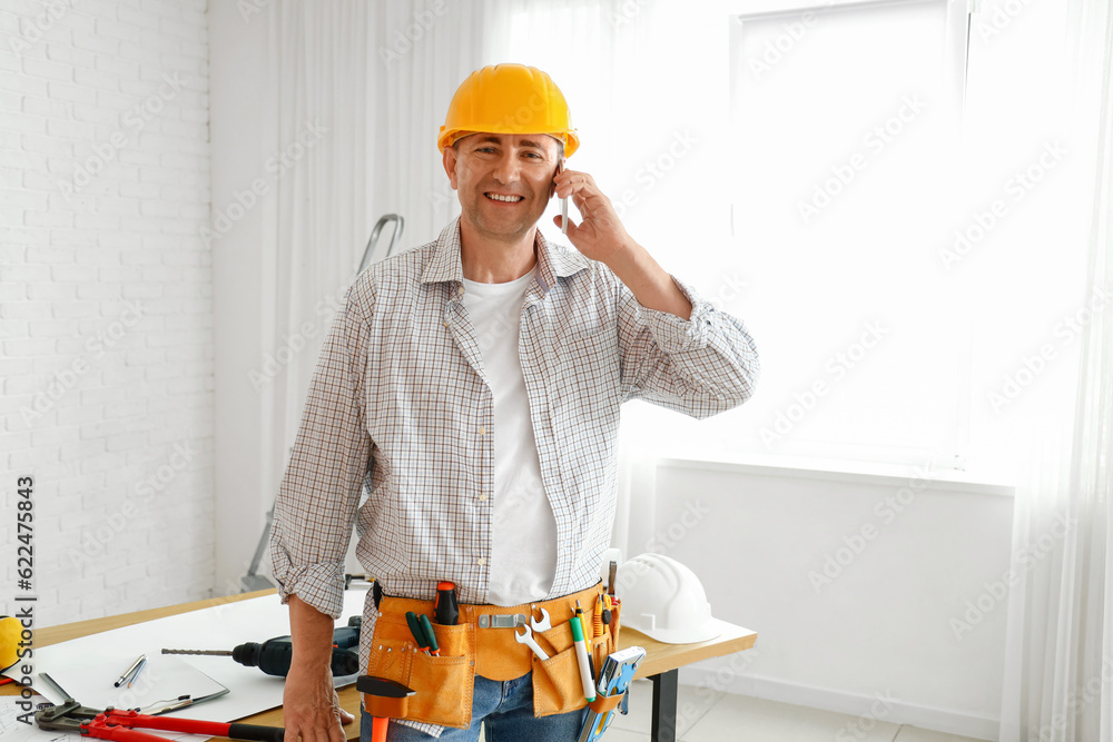 Mature builder talking by mobile phone in room