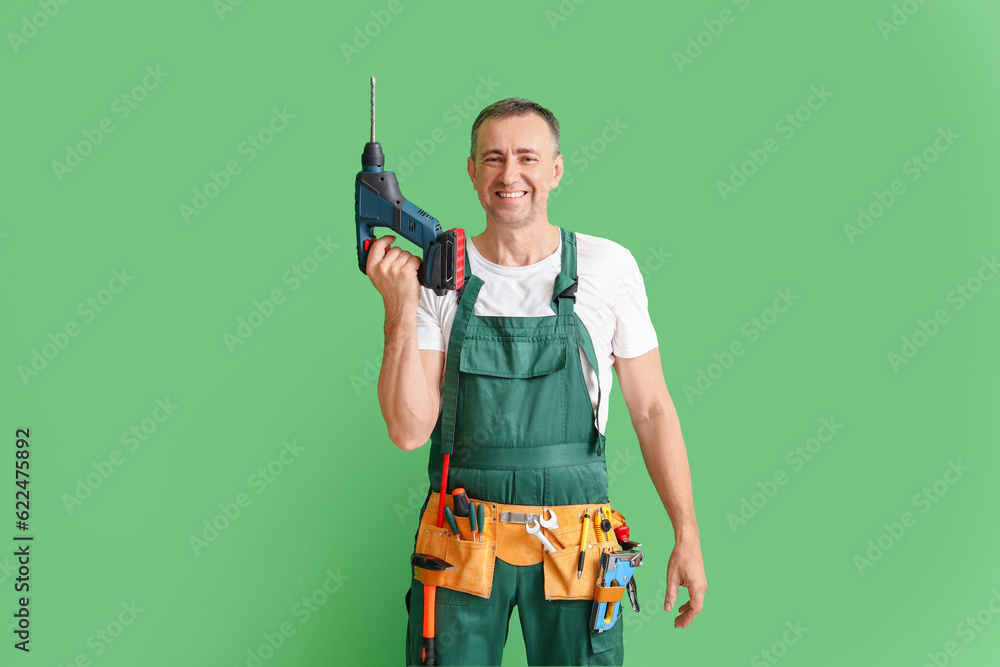 Mature builder with drill on green background