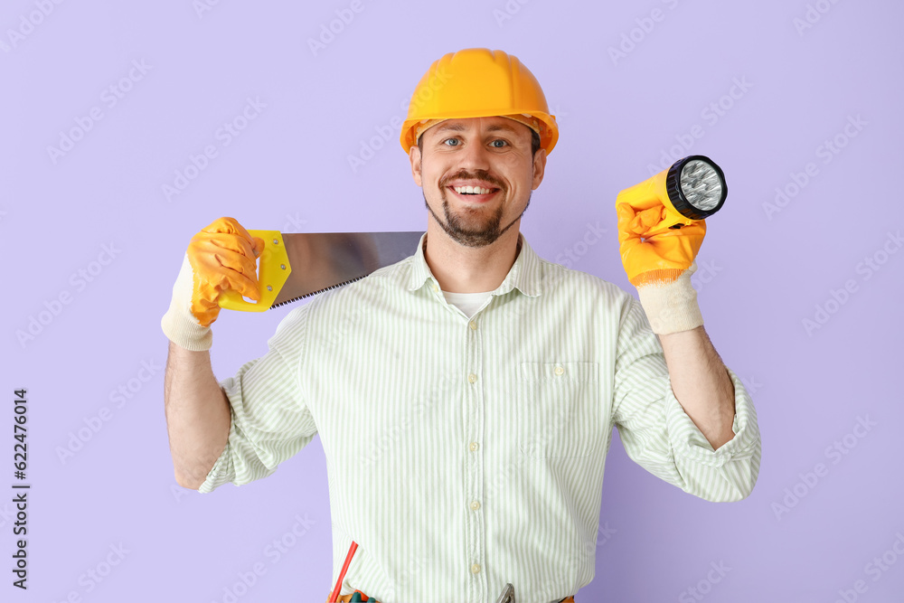 Male builder with handsaw and flashlight on lilac background