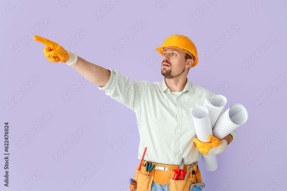 Male builder with house plans pointing at something on lilac background