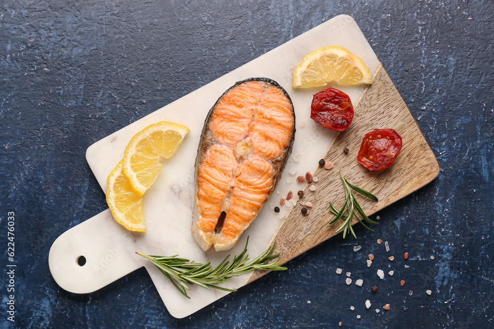 Board with tasty grilled salmon steak on blue background