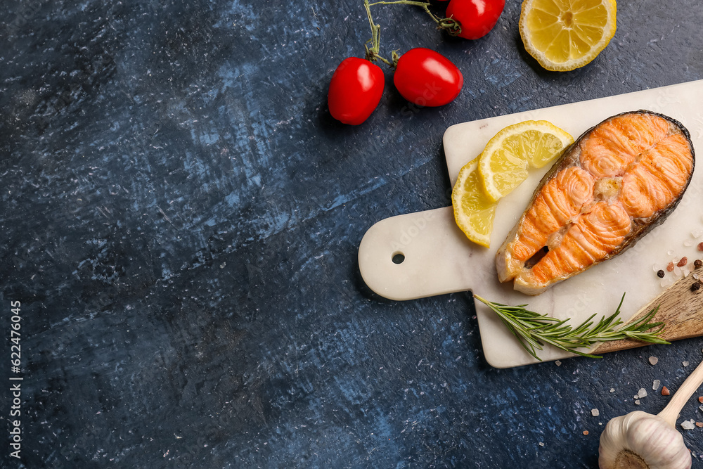 Board with tasty grilled salmon steak on blue background