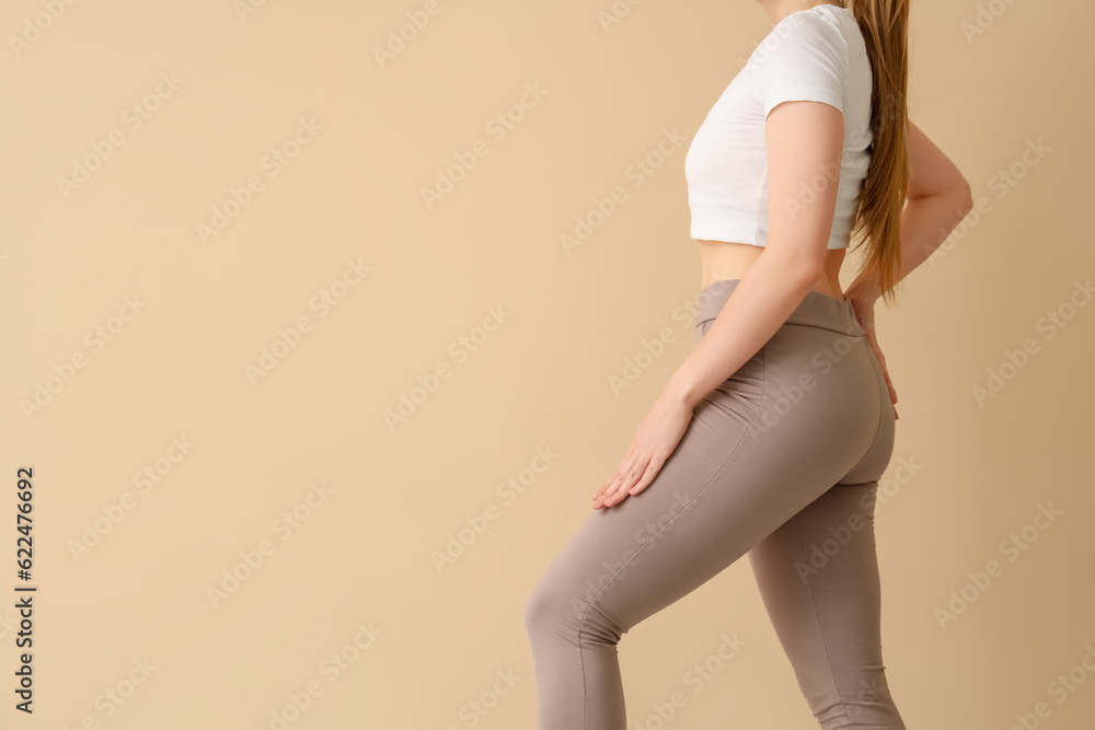 Young woman in sportswear on  beige background