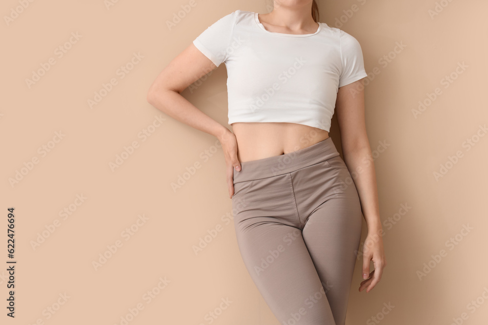 Young woman in sportswear on  beige background