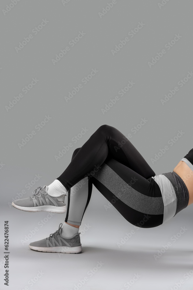 Sporty young woman in leggings on  grey background