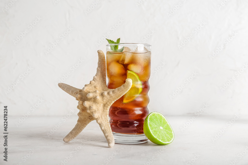 Glass of cold Cuba Libre cocktail and starfish on white background