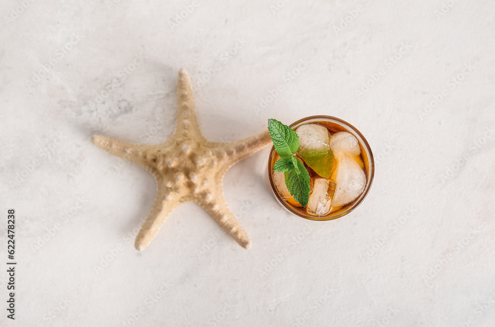 Glass of cold Cuba Libre cocktail and starfish on white background