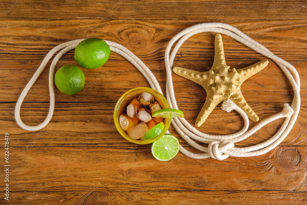 Glass of cold Cuba Libre cocktail and starfish on wooden background