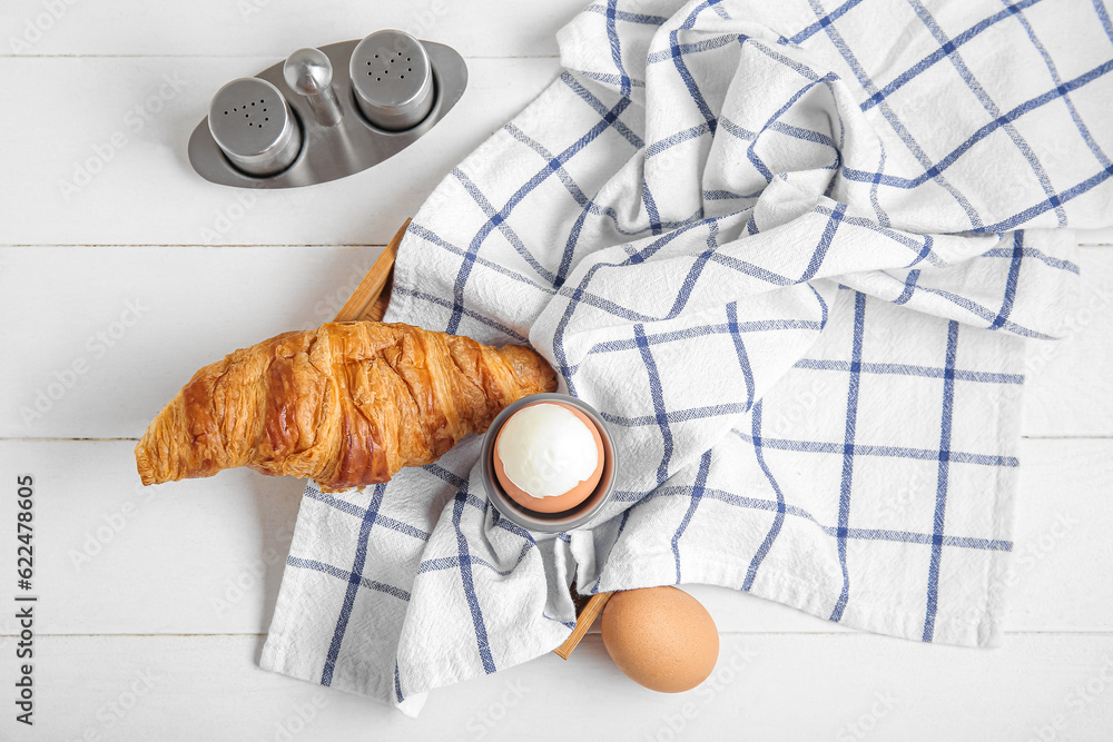 Holder with boiled chicken egg and croissant on white wooden background