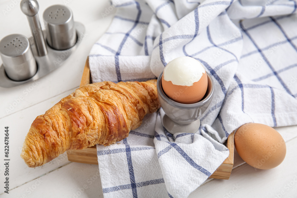 Holder with boiled chicken egg and croissant on white wooden background