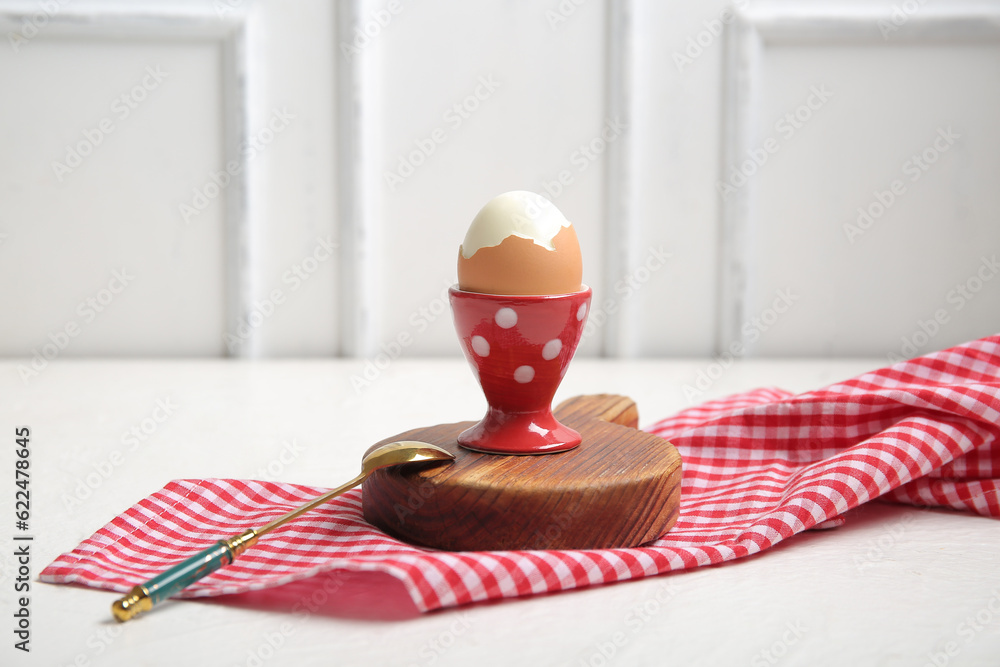 Holder with boiled chicken egg on white background