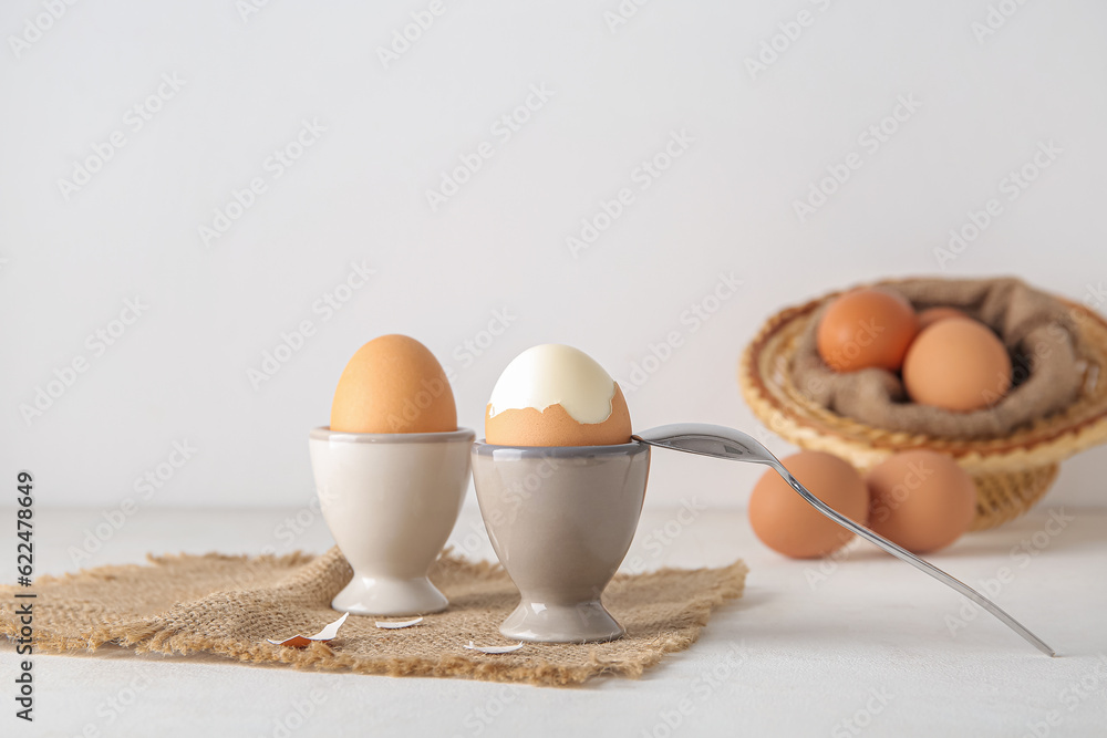 Holders with boiled chicken eggs on white background