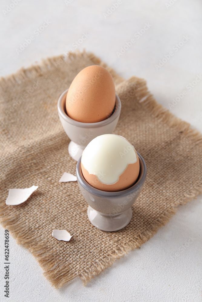 Holders with boiled chicken eggs on white background