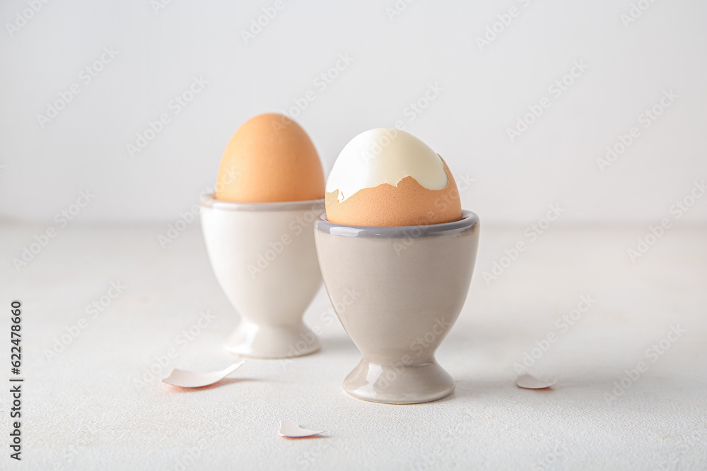 Holders with boiled chicken eggs on white background