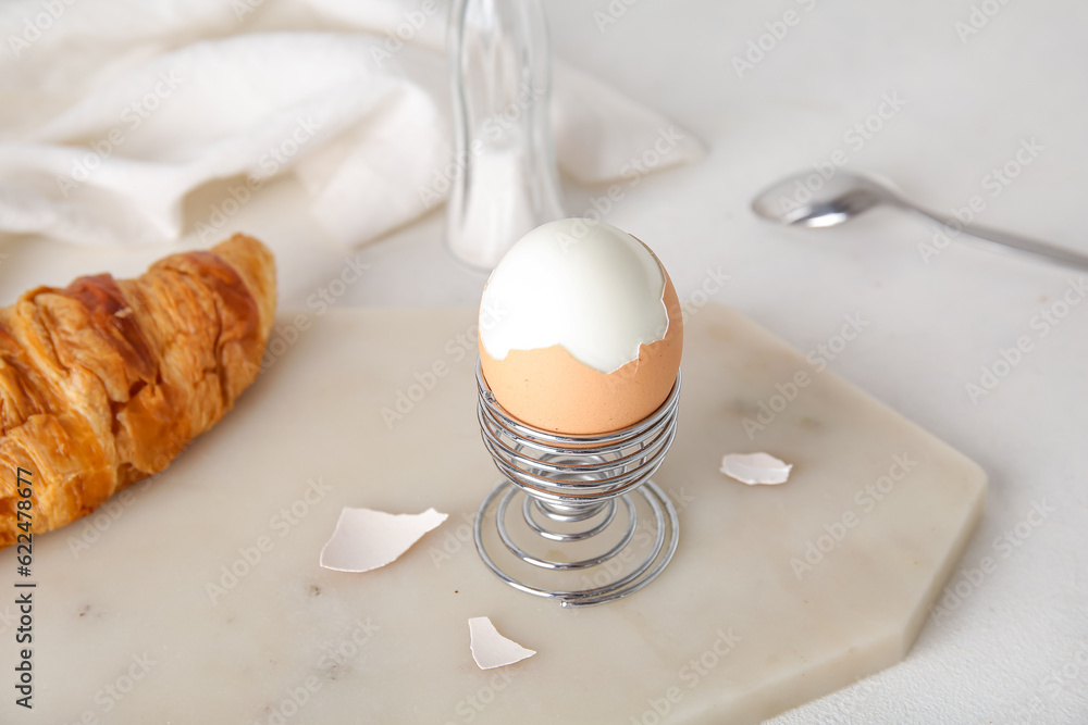 Holder with boiled chicken egg and croissant on white background