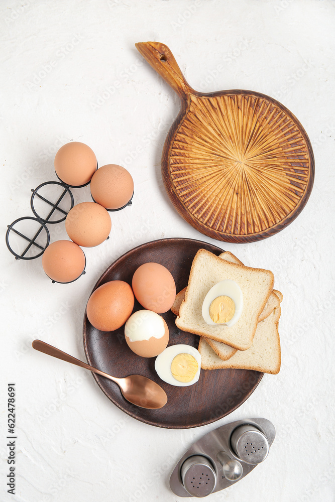 Plate and holder with boiled chicken eggs on white background