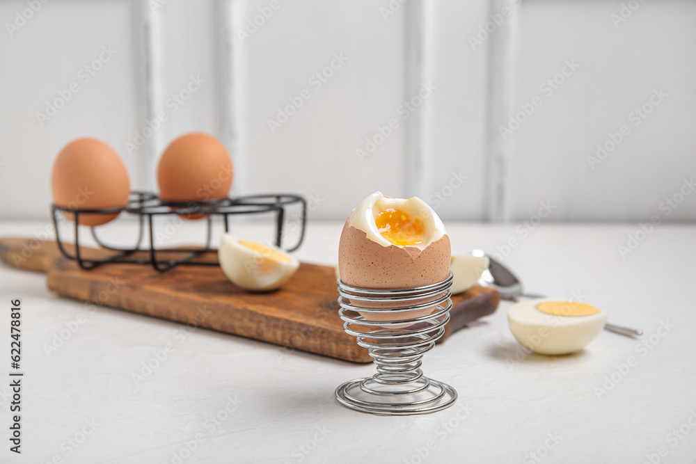 Holders with boiled chicken eggs on white background