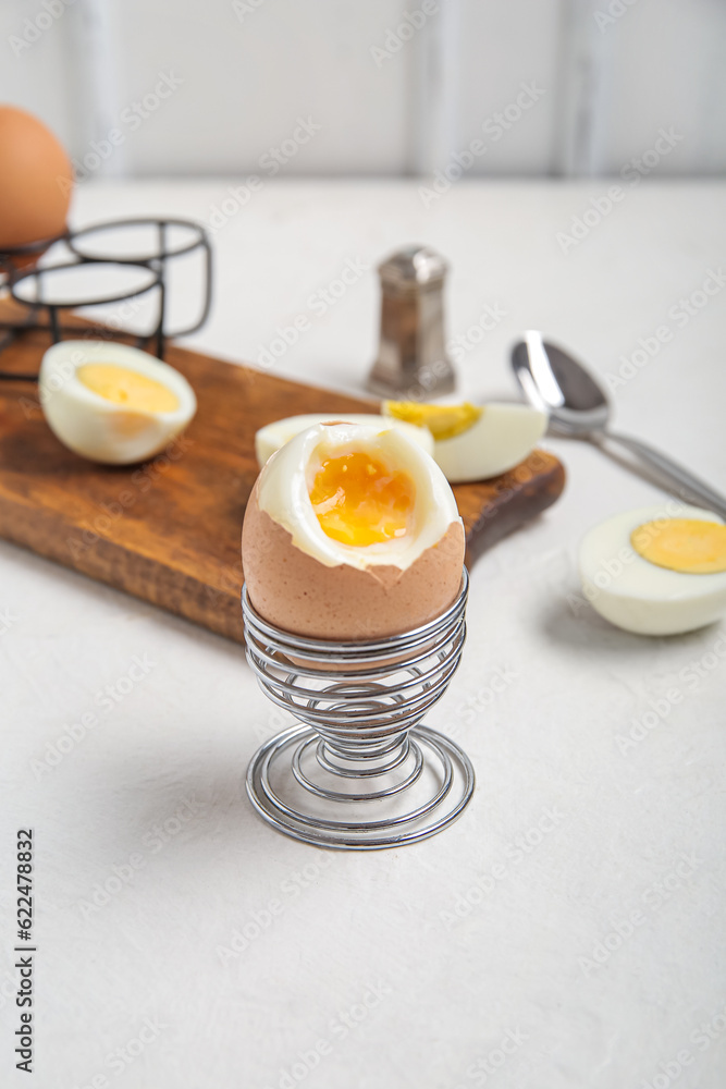 Holder with boiled chicken egg on white background