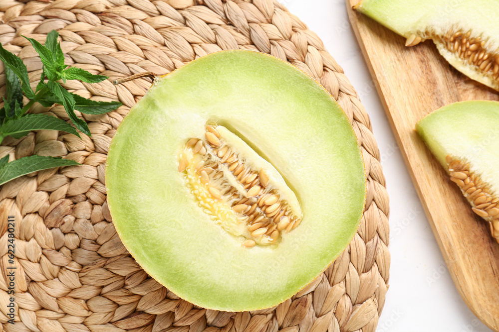 Half of sweet melon and wooden board with pieces on white background