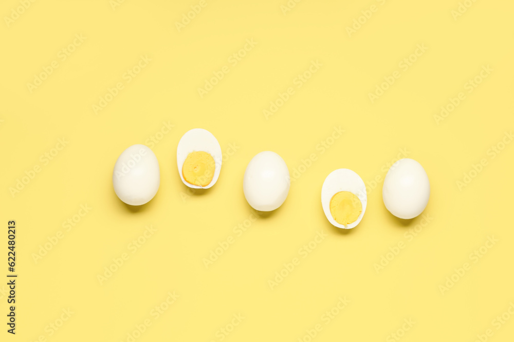 Tasty boiled eggs with halves on yellow background