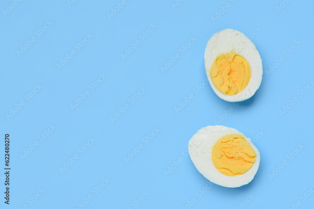 Halves of tasty boiled egg on blue background