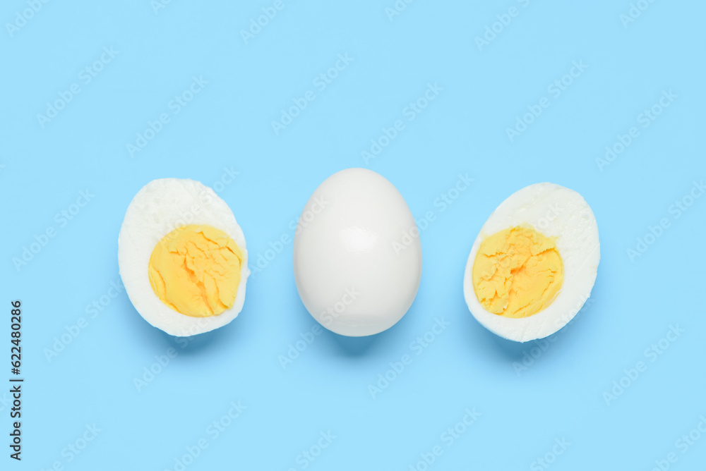 Tasty boiled egg with halves on blue background