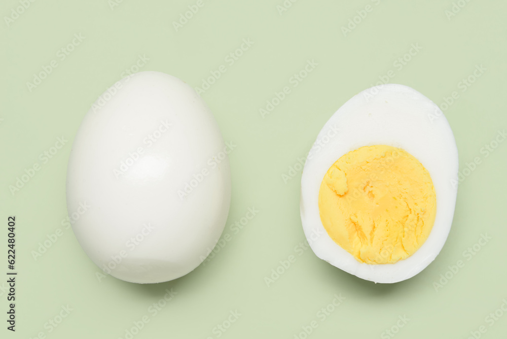 Tasty boiled egg with half on green background