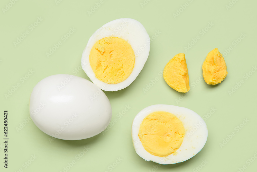 Tasty boiled egg with halves on green background