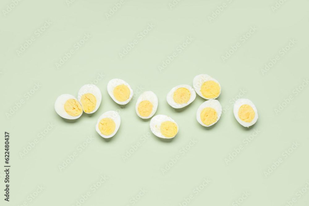 Halves of tasty boiled eggs on green background