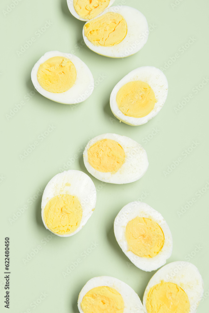 Halves of tasty boiled eggs on green background