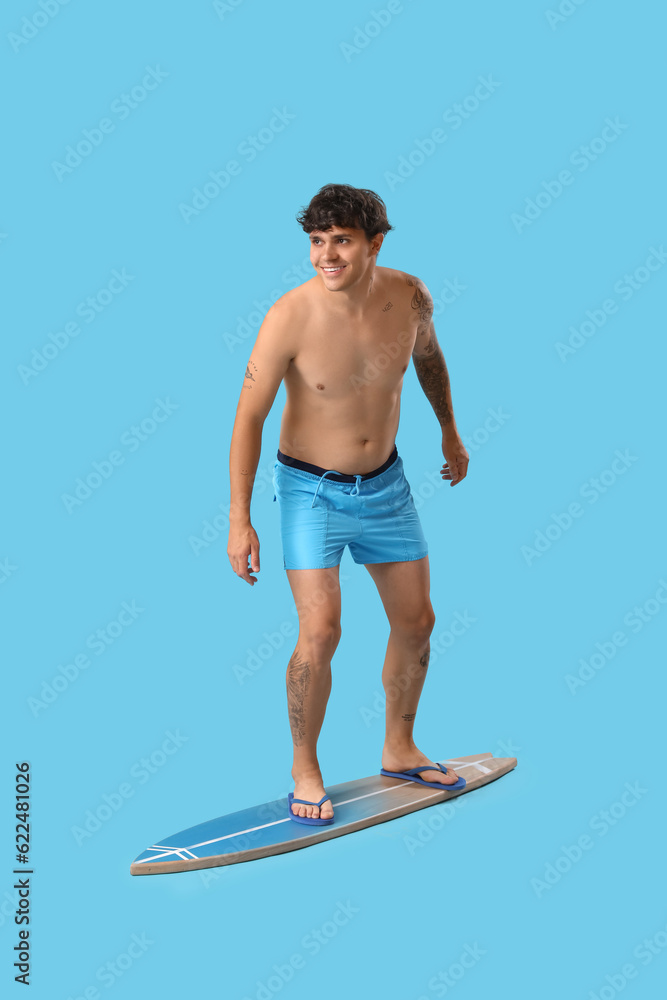 Young man with surfboard on blue background