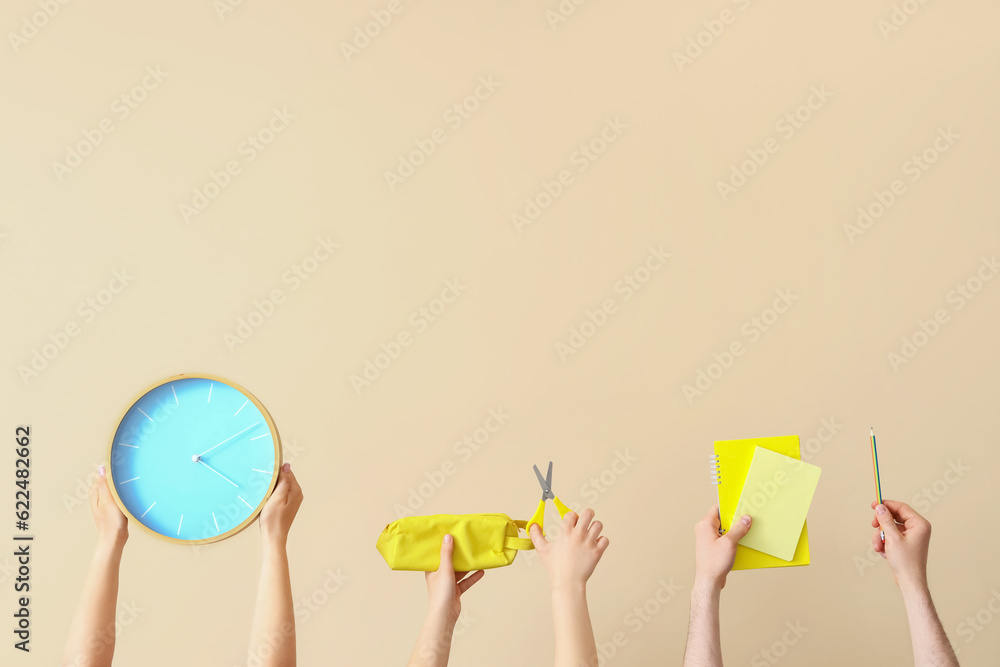 Many hands holding school supplies on beige background