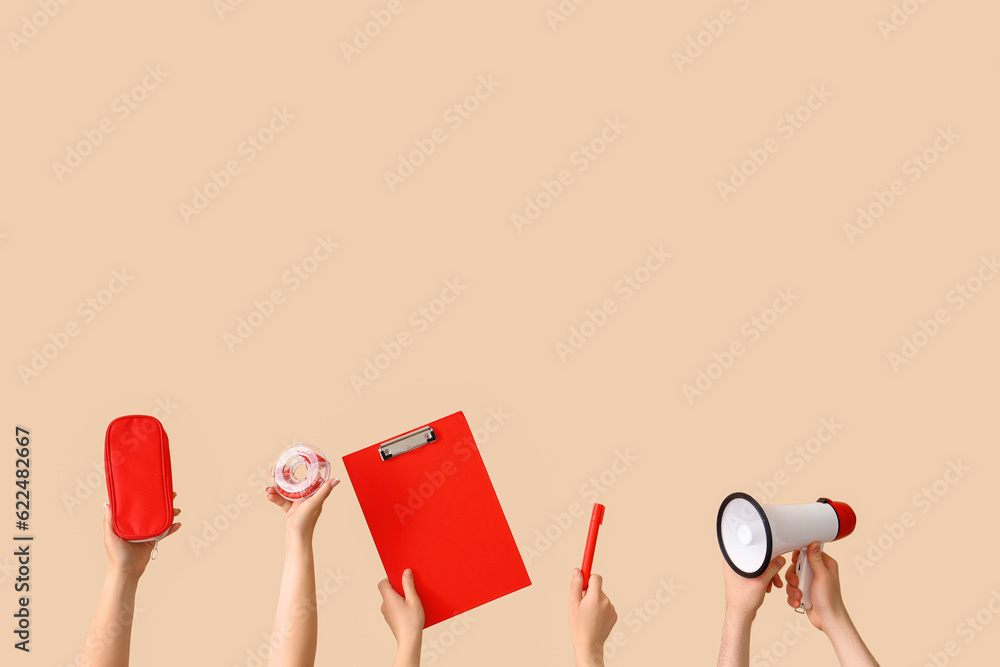 Many hands holding school supplies on beige background