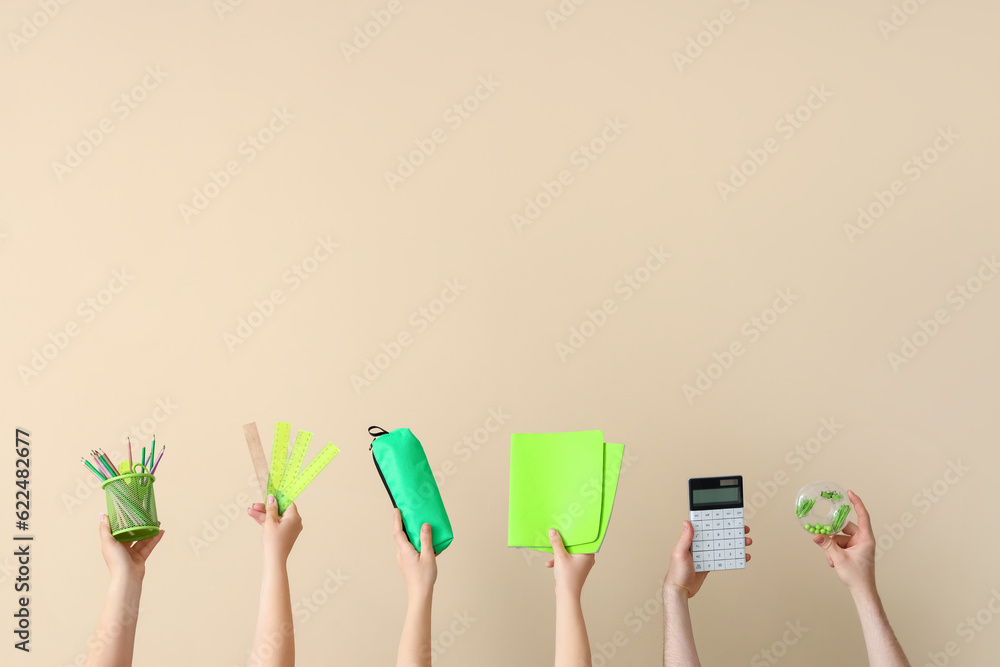 Many hands holding school supplies on beige background