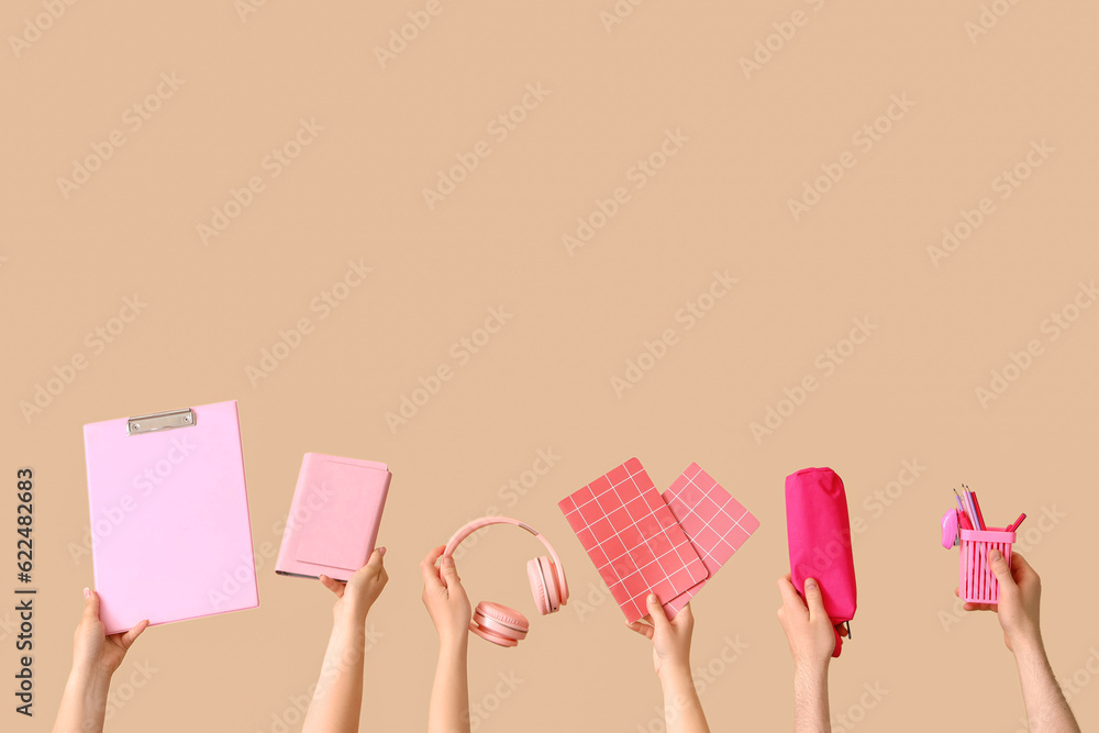 Many hands holding school supplies on beige background