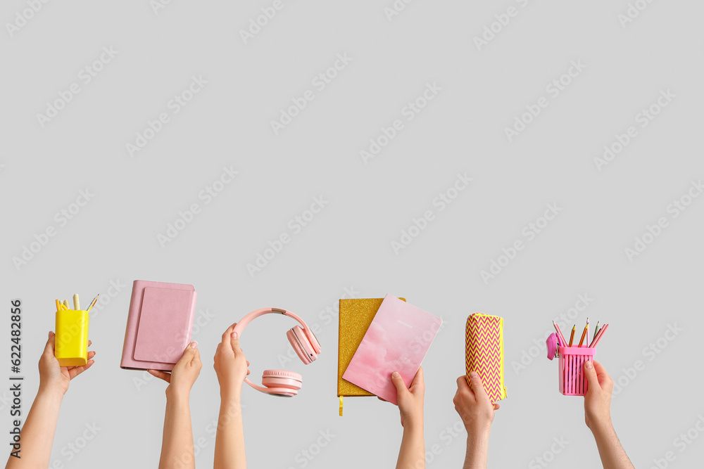 Many hands holding school supplies on grey background