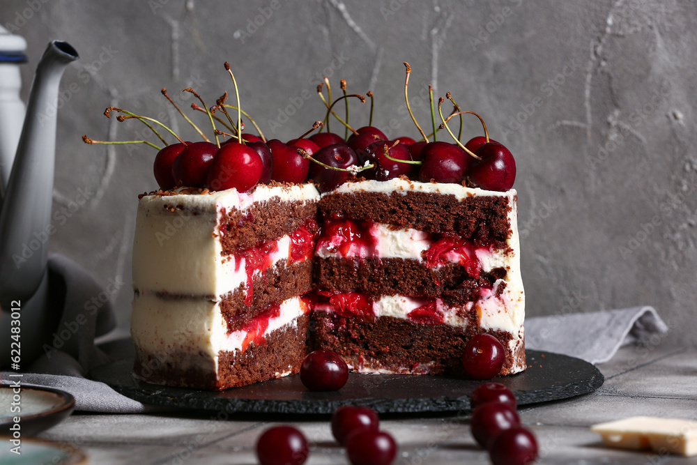 Board with tasty cherry cake on grey tile table