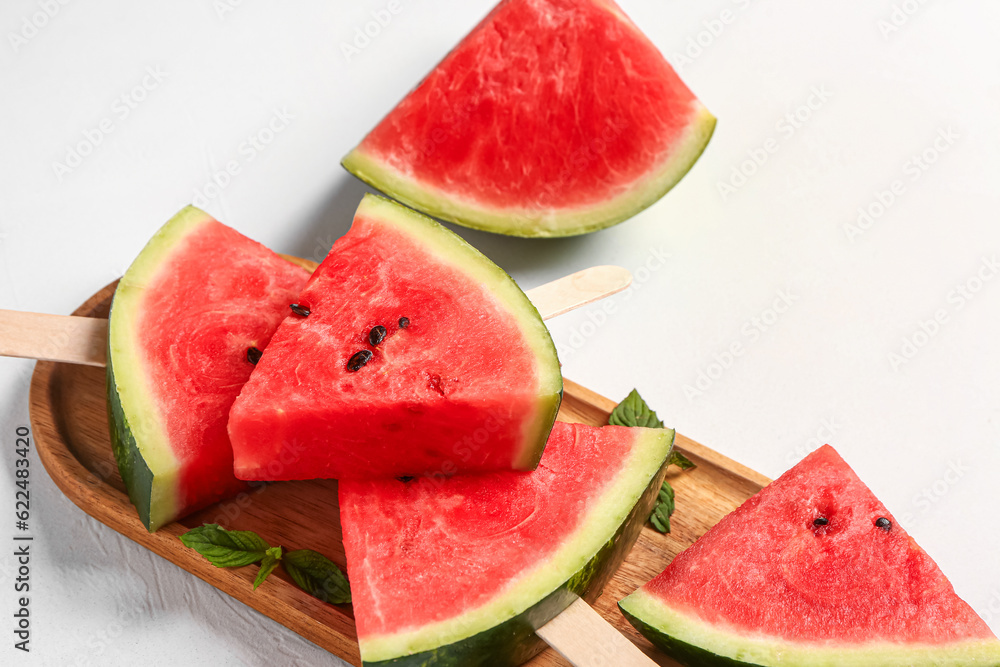 Wooden board with sweet watermelon sticks and mint on white background