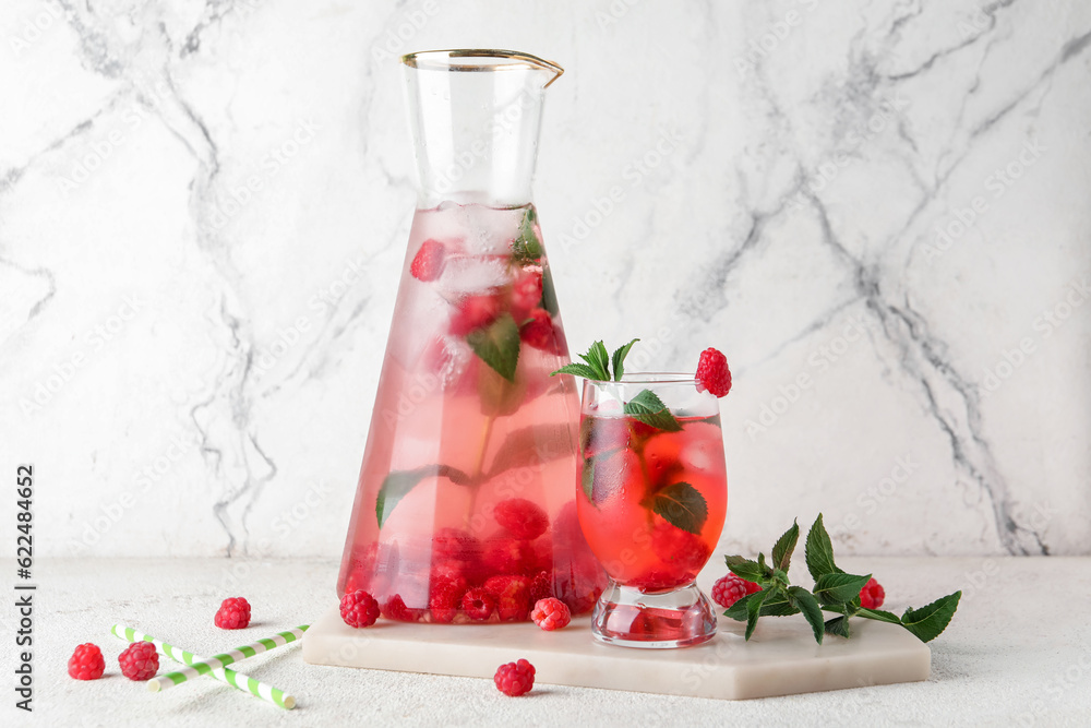 Bottle and glass of fresh raspberry lemonade with mint on white background