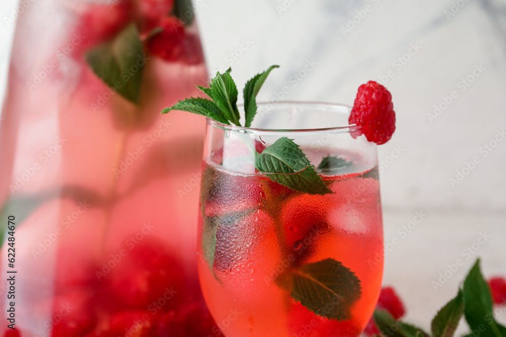 Bottle and glass of fresh raspberry lemonade with mint on white background