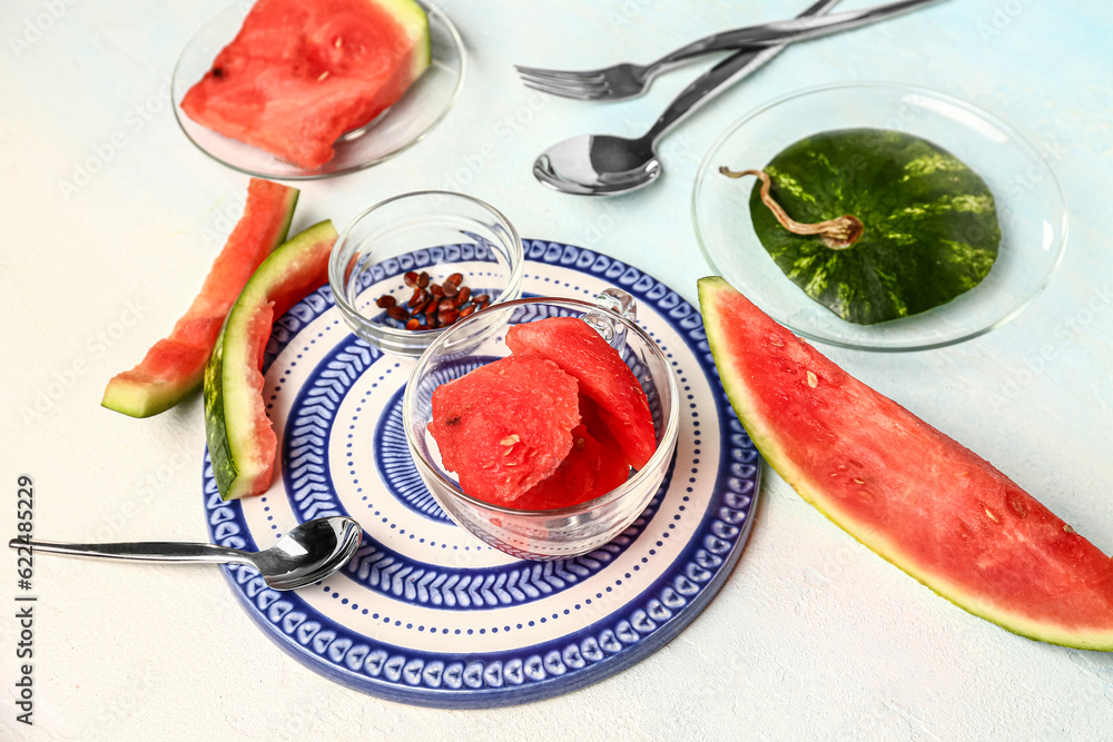 Plate and glass cup with pieces of fresh watermelon on white background