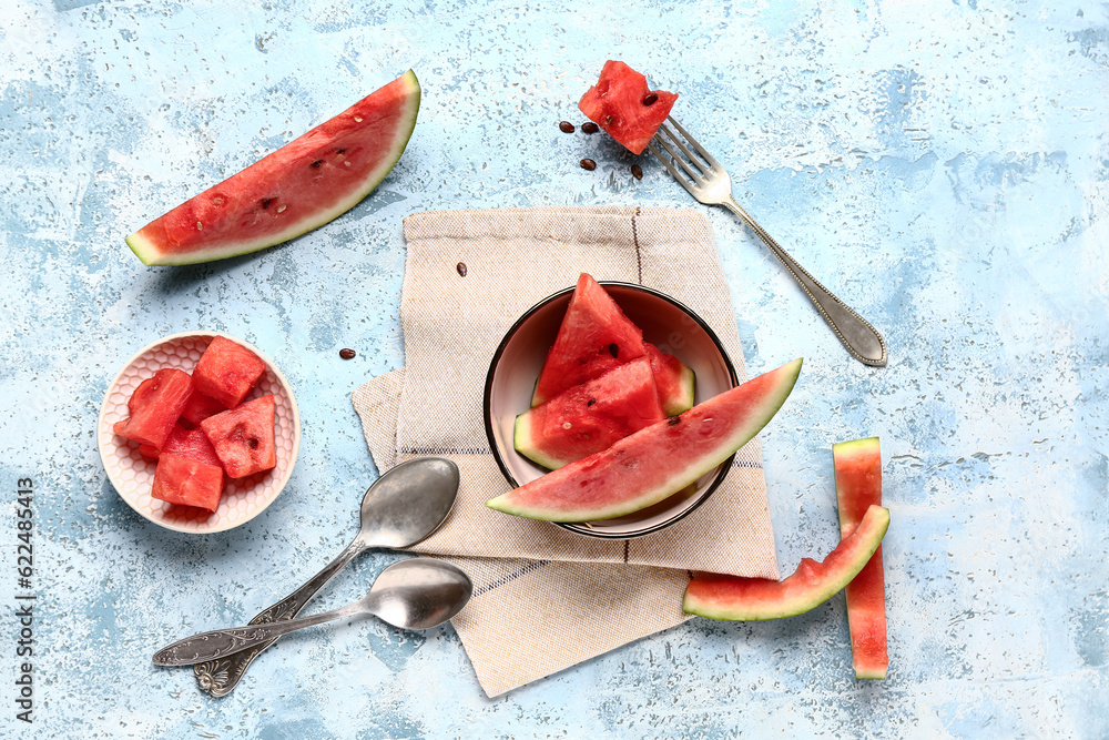 Bowls with pieces of fresh watermelon on blue background