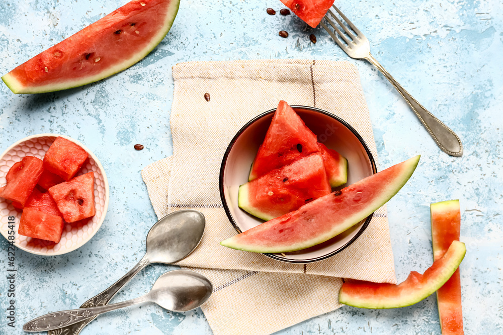 Bowls with pieces of fresh watermelon on blue background